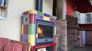 Un poêle à bois aux couleurs vives, dans lequel le feu crépite, est placé contre un mur sur lequel se trouve une cheminée en briques.
