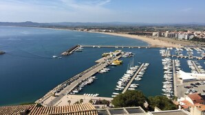 Un port de plaisance avec des bateaux amarrés, une jetée s’avançant dans l’eau et une plage en arrière-plan.