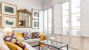 Ein Wohnzimmer mit einer Couch, einem Glastisch und einem gemusterten Teppich.