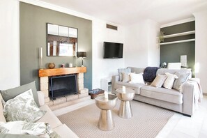 Relax in style with a comfortable sofa set, modern fireplace, and flat-screen TV.