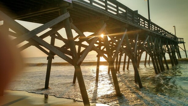 A pier structure with a wooden deck and railings, extending over a body of water. - COMPLETELY RENOVATED! Immaculately clean and new. See new photos! (Surfside Beach)