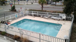 A rectangular pool with a white fence, shallow water warning signs, and lounge chairs. - COMPLETELY RENOVATED! Immaculately clean and new. See new photos! (Surfside Beach)