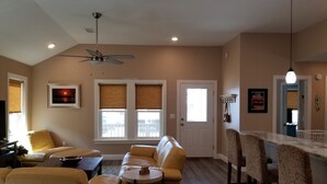 A living room with a sofa, a coffee table, and a ceiling fan. There is a door with a window and a picture frame on the wall. - Walk to beach! Cottage perfect for families. (Kill Devil Hills)