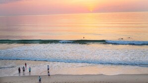 A beach scene with people walking along the shore during sunset. - Walk to beach! Cottage perfect for families. (Kill Devil Hills)