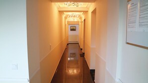 Un pasillo de hotel con piso pulido, un candelabro y un cuadro en la pared.