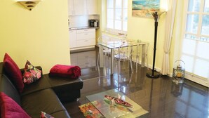 Una sala de estar con un sofá negro, una mesa de centro de vidrio transparente y un comedor con una mesa y sillas de vidrio.
