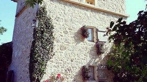 Un bâtiment en pierre avec un toit en pente, des murs couverts de lierre et une petite fenêtre.