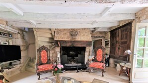 Un salon de style rustique avec une cheminée en pierre, des meubles en bois et un téléviseur.