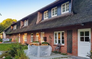 A traditional brick house with a thatched roof, multiple windows, and a covered outdoor seating area. - Nice home in Langenhorn with WiFi (Langenhorn)