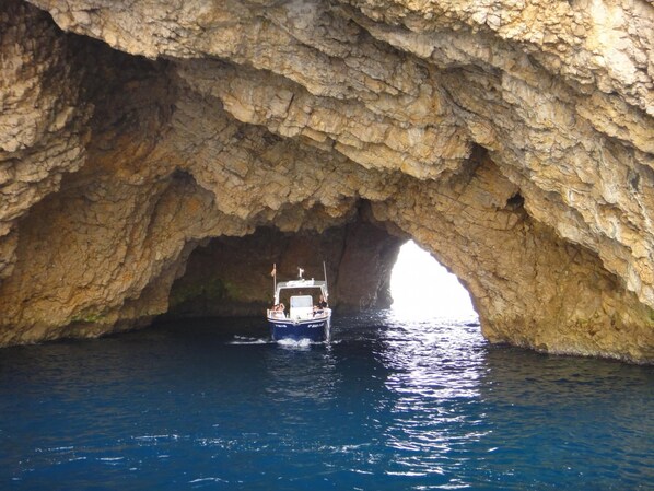 Um barco navegando por um arco natural de rocha.