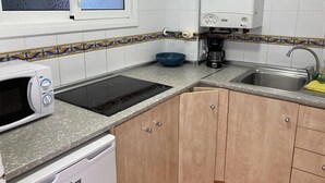 A kitchen with a microwave, stove, coffee maker, sink, and cabinets.