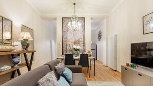 En moderne stue med sofa, spisebord og en lysekrone.