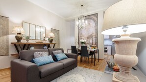 En moderne stue med en grå sofa, et spisebord og en lysekrone.