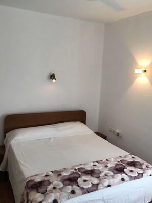 Cozy retreat with a single bed, bedside table, and convenient power outlet.