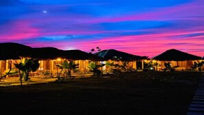 A resort with thatched-roof huts, a clear night sky, and a walkway leading to the buildings. - Blue Waters Arugambay (Pottuvil)