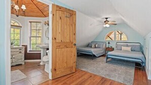 A cozy attic bedroom with a sloped ceiling, a wooden door, two beds, a ceiling fan, and a view of the outdoors through a window. - Perfect lakefront house in quite cove! Walking distance to Mt Lake Marina. <br> (Rocky Top)