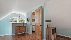 A room with a sloped ceiling, wooden flooring, a wooden dresser, a door, and a stone accent wall. - Perfect lakefront house in quite cove! Walking distance to Mt Lake Marina. <br> (Rocky Top)