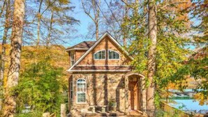 A stone house with a gabled roof, a front porch, and a pathway leading to the entrance. - Perfect lakefront house in quite cove! Walking distance to Mt Lake Marina. <br> (Rocky Top)