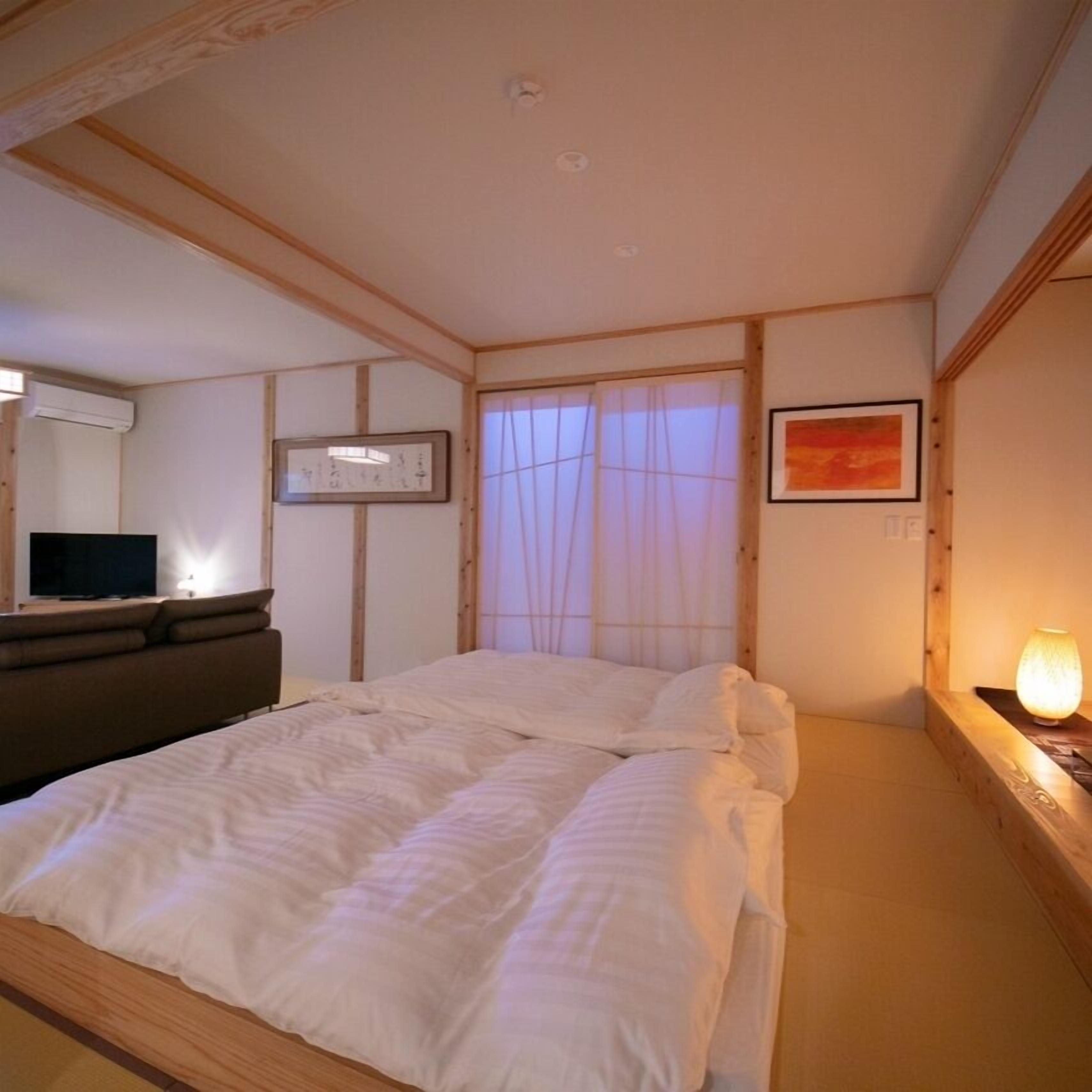 Ein Schlafzimmer mit Bett, Fernseher, Bilderrahmen und Lampe.
