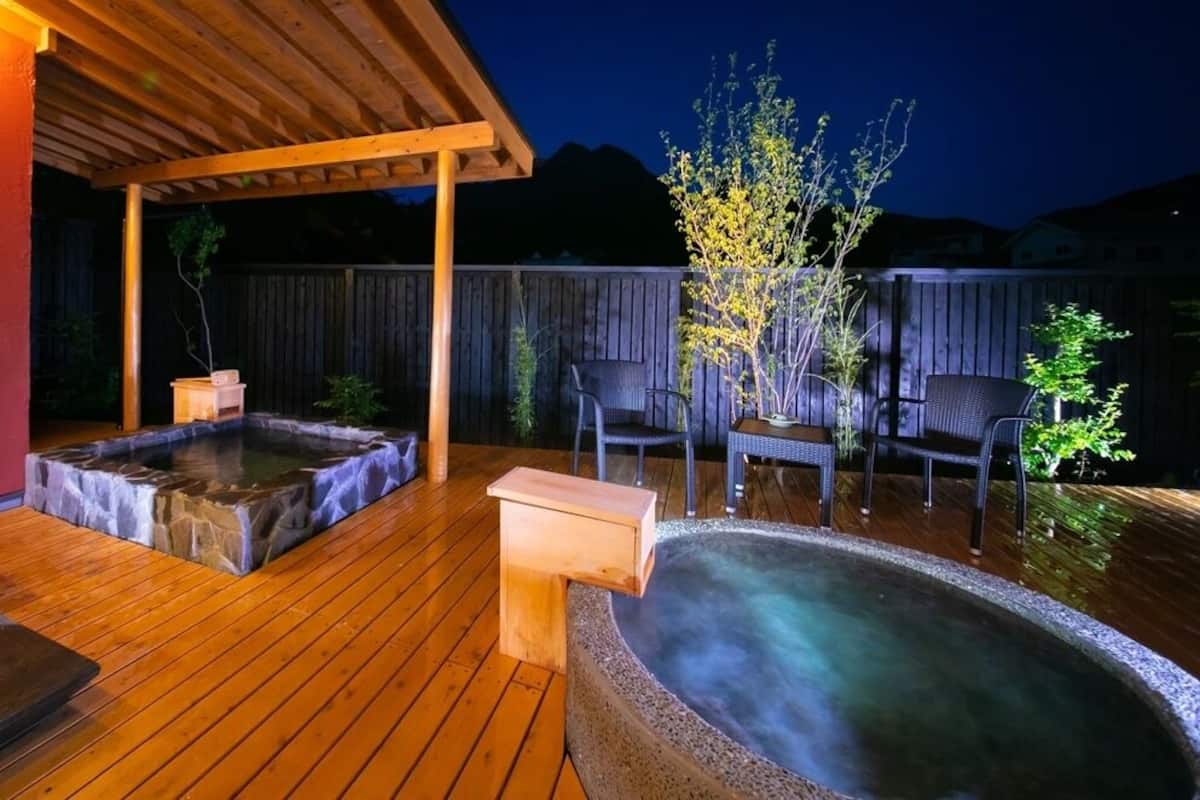 Ett trädäck med bubbelpooler, en träpergola och utomhusmöbler.
