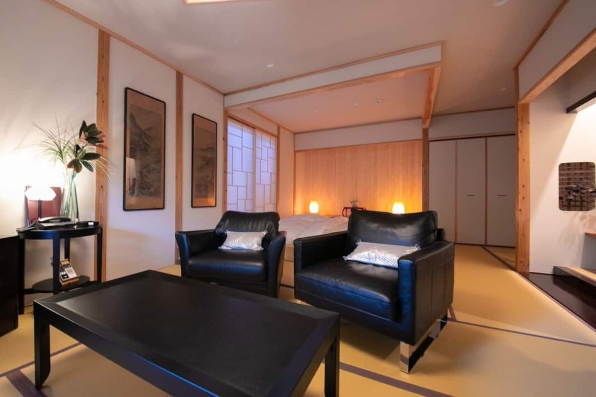 Ett modernt vardagsrum med en soffa, fåtöljer, ett soffbord, en tv och en prydnadsväxt.