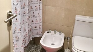 Ein Badezimmer mit einer weißen Toilette, einem Bidet, einem roten Teppich in Herzform auf dem Boden und einer Duschvorhang mit Yoga-Posen.