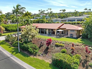 A residential property with a red-tiled roof, a covered patio, and a well-maintained garden with various plants and flowers.