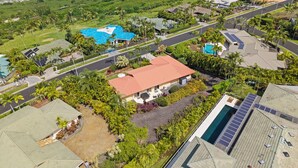 Vista aérea de una zona residencial con casas, piscina y vista al océano.