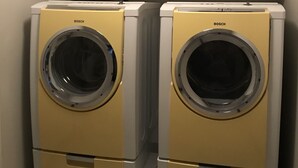 Two Bosch washing machines in a laundry area with white cabinets above. - Fully Renovated 2 Bed, 1 Bath Apartment near 8th Street (Saskatoon)