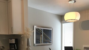 A modern kitchen with stainless steel appliances, a coffee maker, and a framed picture of a bridge. - Fully Renovated 2 Bed, 1 Bath Apartment near 8th Street (Saskatoon)