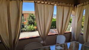 A glass-top table with wicker chairs in a room with beige curtains. - Private Villa with Large Garden & Veranda – Relaxation & Comfort in Budoni (Budoni)
