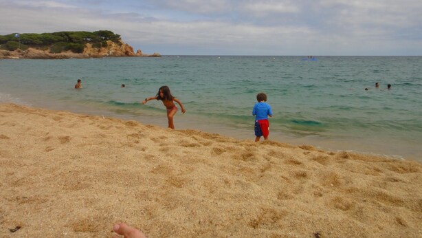A sandy beach with clear water, a rocky coastline, and a few people in the distance. - Apartments very close to the beach. Ref.LLORET SUN-24 (Lloret de Mar)