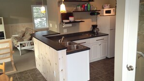 Una cocina compacta con una isla central, muebles blancos y un refrigerador pequeño.