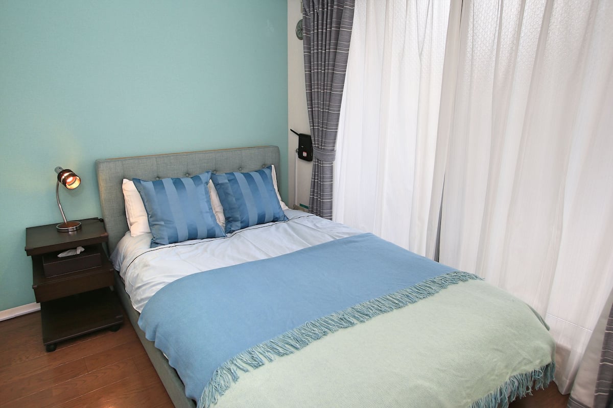 A bedroom with a bed, nightstand, and a wall-mounted lamp.