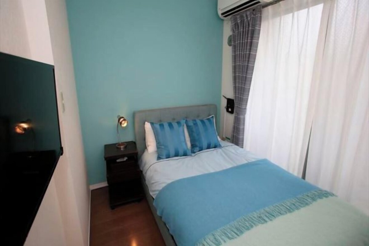 Een slaapkamer met een bed, nachtkastje, lamp en een airconditioning.
