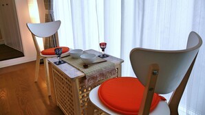 A dining area with a table set for four, including bowls, a wine glass, and a spoon. There are two chairs with orange cushions. - Numero Uno Tokyo (Tokyo)