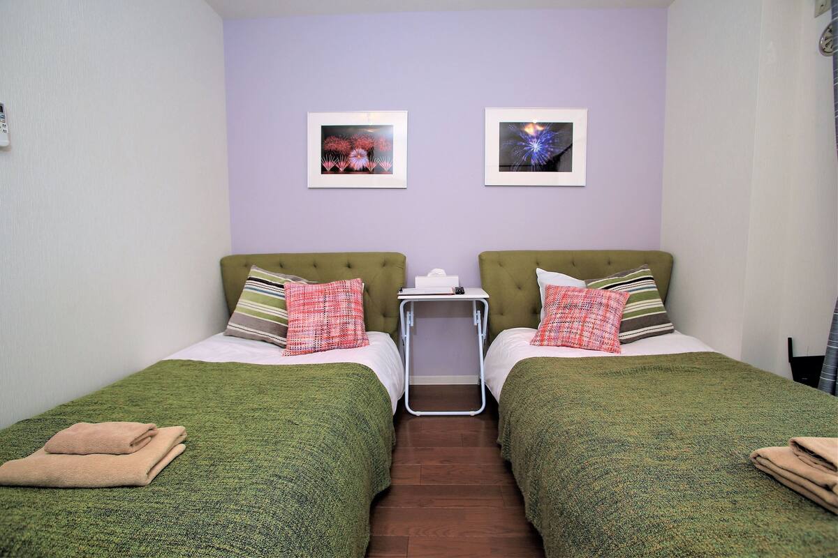 A twin room with two beds, a small table, and two framed pictures on the wall.