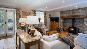 A cozy living room with a stone fireplace, a television, and a comfortable seating area.