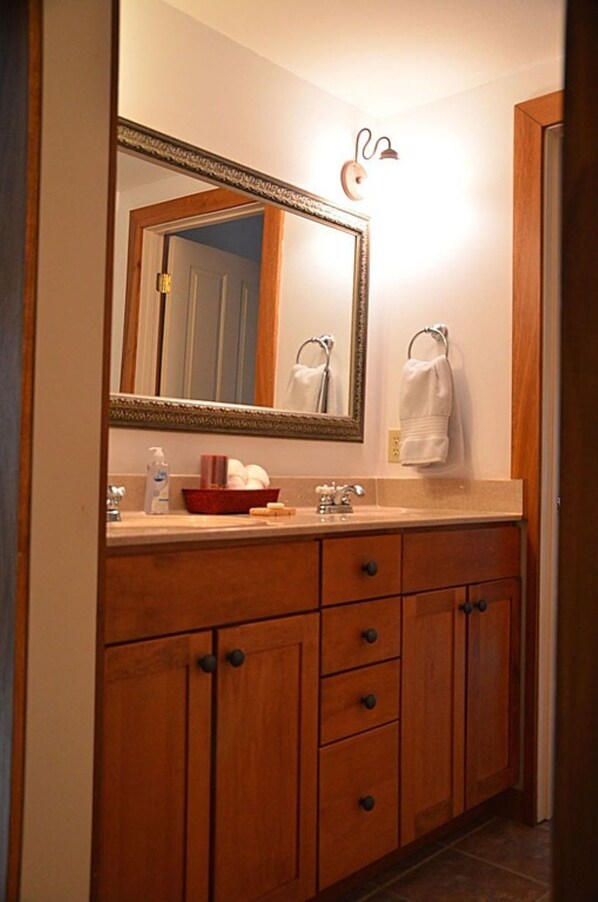 A bathroom with a wooden vanity, a large mirror, a towel rack, and a sink with toiletries.