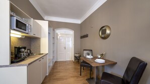 A compact kitchen with a microwave, coffee maker, and a dining area with a table set for two. - OLD TOWN - STUDIO MICHALSKA max 4 pers (Prague 1)