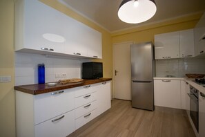 Een moderne keuken met witte kasten, een roestvrijstalen koelkast en een houten aanrecht.