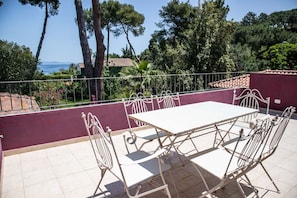 A terrace with a white table and metal chairs, surrounded by a purple wall and a metal railing. - Villa with pool and beach access (Capoliveri)
