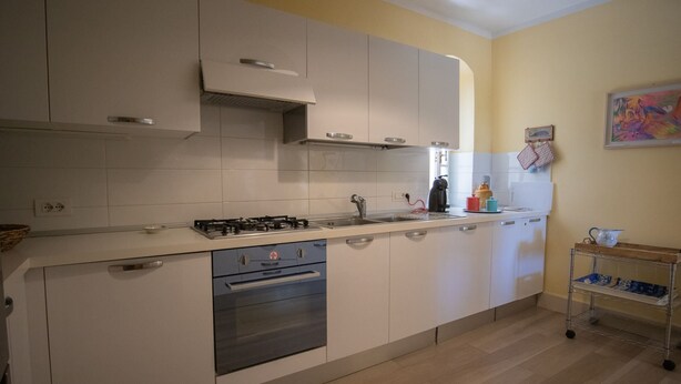 Une cuisine moderne avec des meubles blancs, une cuisinière en acier inoxydable et un plan de travail en bois.