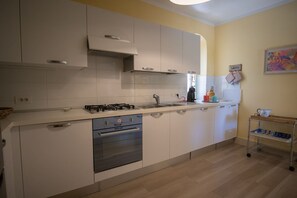 Moderni keittiö, jossa on valkoiset kaapit, ruostumattomasta teräksestä valmistettu liesi ja puinen työtaso.