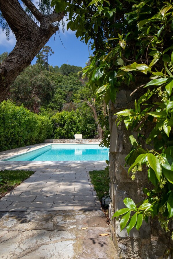 A swimming pool with a stone pathway leading to it, surrounded by lush greenery and a clear sky. - Villa with pool and beach access (Capoliveri)