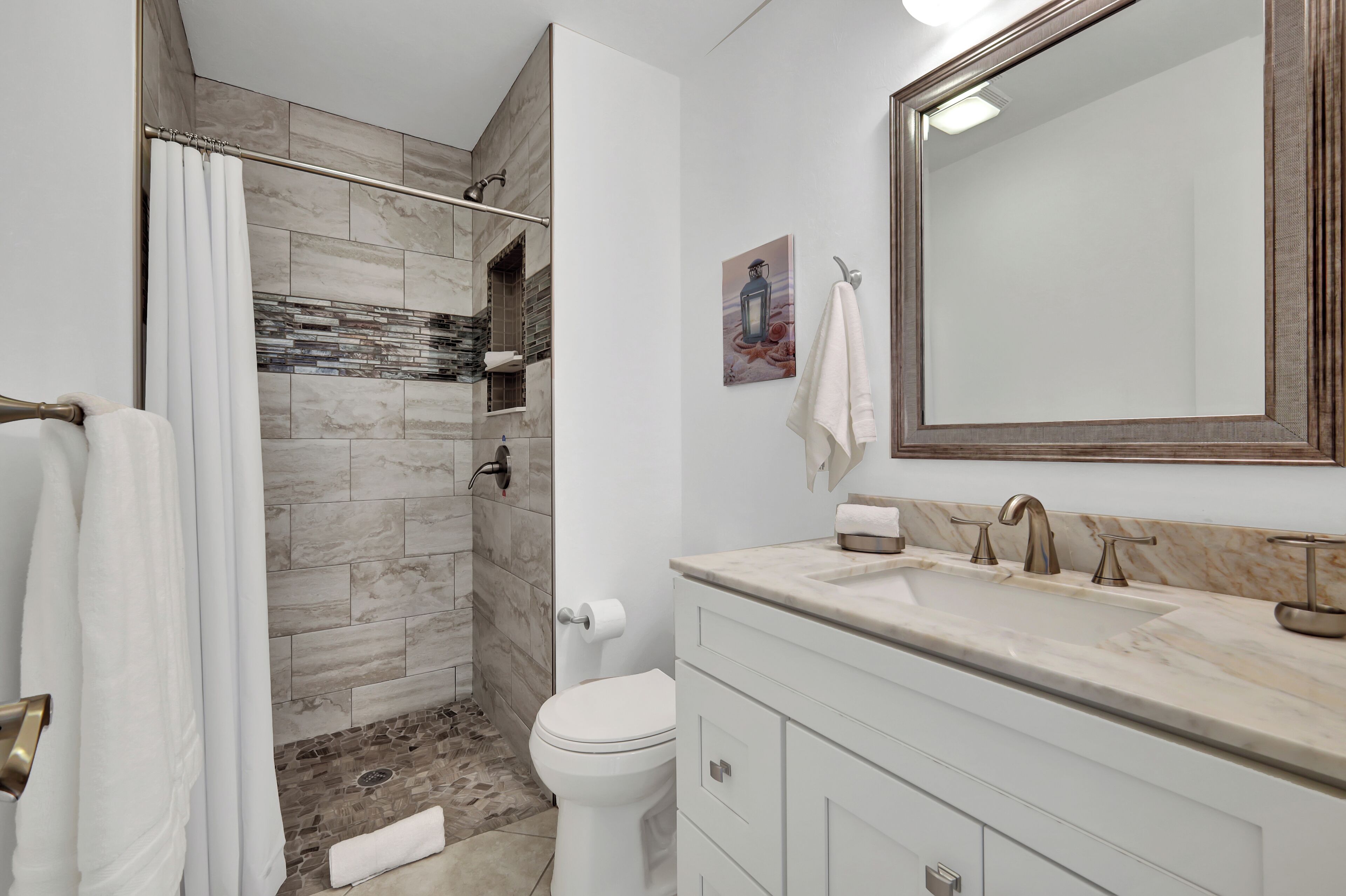 A modern bathroom with a shower, toilet, and vanity.