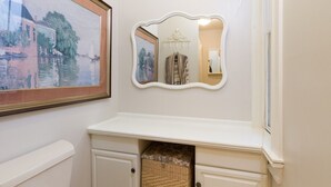 A bathroom with a white vanity, a mirror with an ornate frame, and a framed painting above the mirror. - Unit 2, 1st floor 1 Bdrm, walk to mansion and beach (Newport)