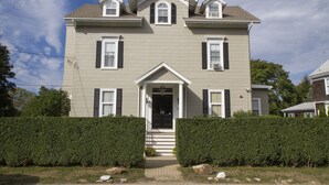 A two-story house with a front porch, a central entrance, and a symmetrical facade. - Unit 2, 1st floor 1 Bdrm, walk to mansion and beach (Newport)
