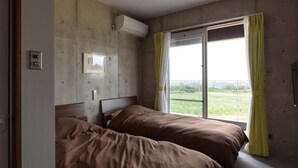 Un dormitorio con dos camas, una ventana con cortinas, un aire acondicionado y vistas al exterior.