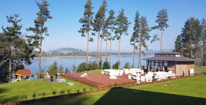 Relax on the lakeside deck with comfortable lounge chairs and a sheltered seating area amidst lush trees and a serene lake view.